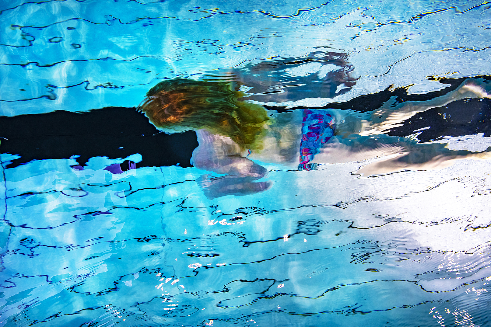 Flicka simmar under vatten.